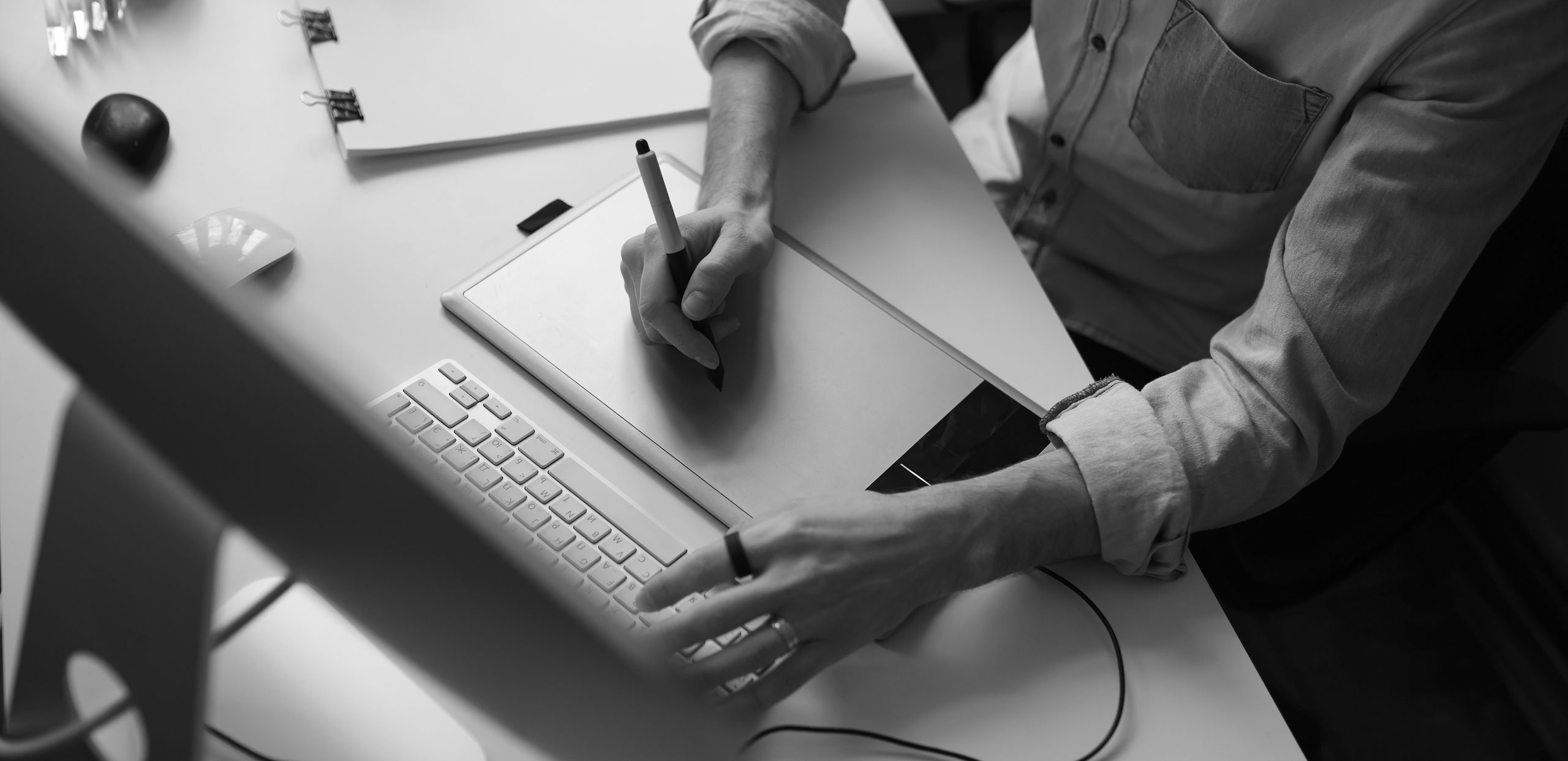 Young male designer using graphics tablet while working with com Designer hands using graphics tablet while working with computer at studio or office. Top side view.